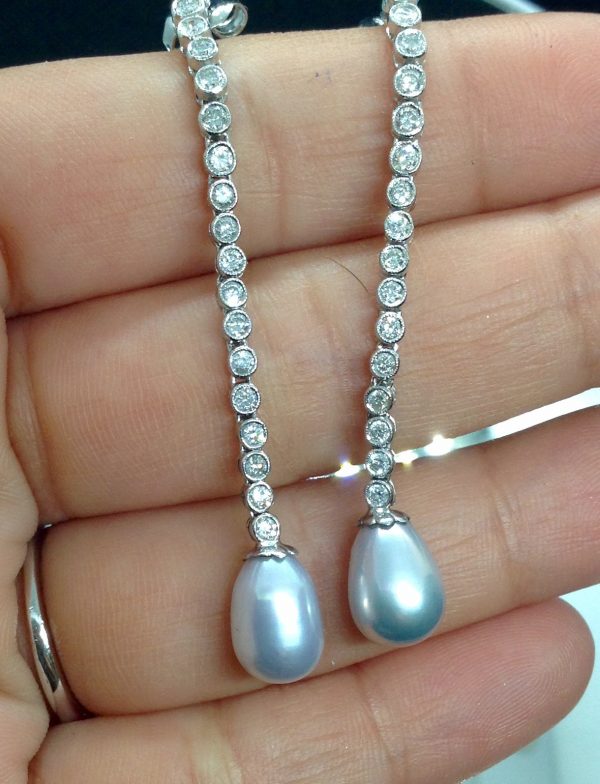 A woman holding a 10mm South Sea Pearl Drops with 1.00 Ct Diamond Long Drop Dangle 18k White Gold Earrings