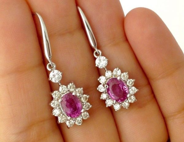 A person holding two 14K White Gold 2.0 CT Pink Sapphire Flower Earrings W/ 1.04 CT VS Diamond Halo