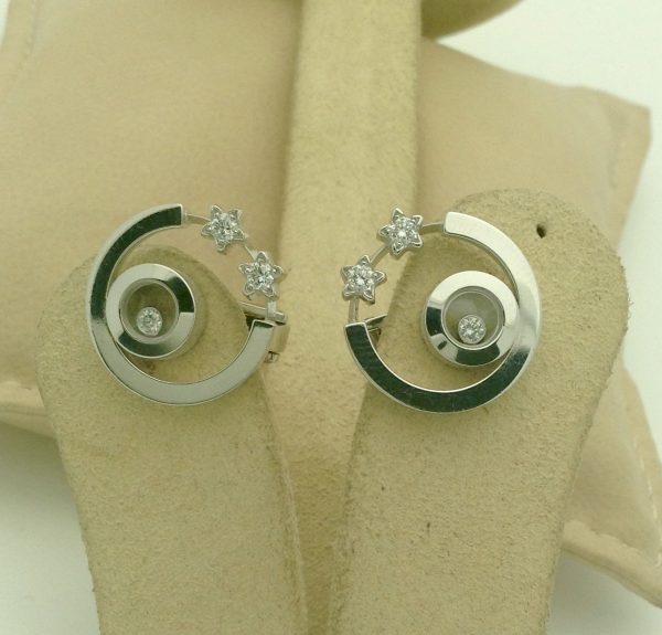 Two pieces of Happy Diamonds Stars By Chopard 18k White Gold Earrings on a piece of carton
