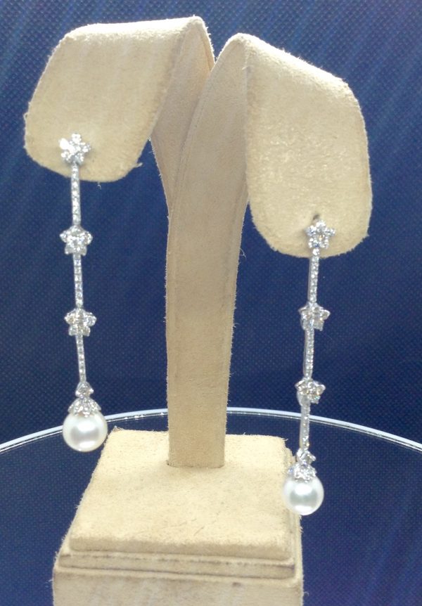 A front view of two 18k White Gold Long Drop 1.50 Ct Diamond Earrings with 8mm South Sea Pearl Drops hanging on fake ears