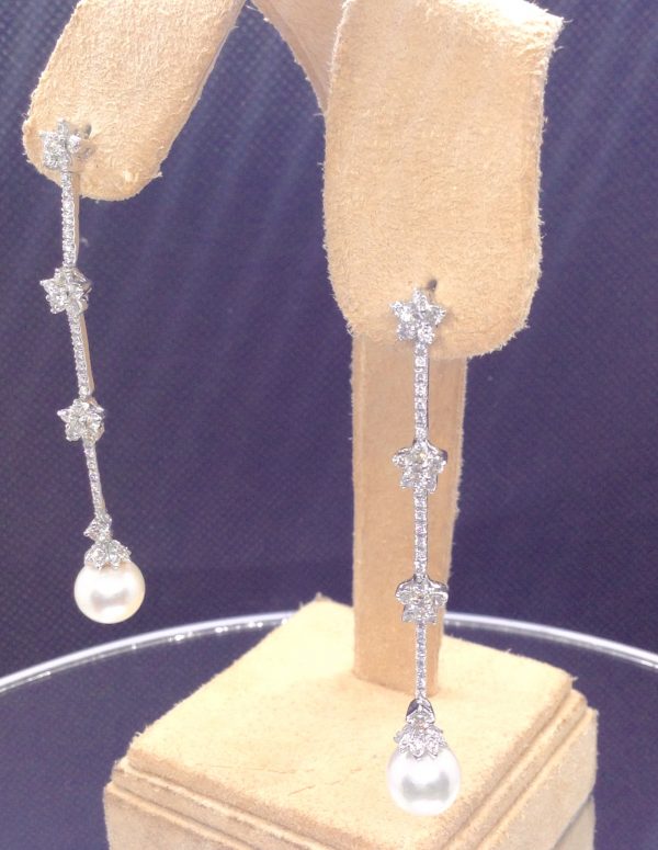 A side view of two 18k White Gold Long Drop 1.50 Ct Diamond Earrings with 8mm South Sea Pearl Drops hanging on fake ears
