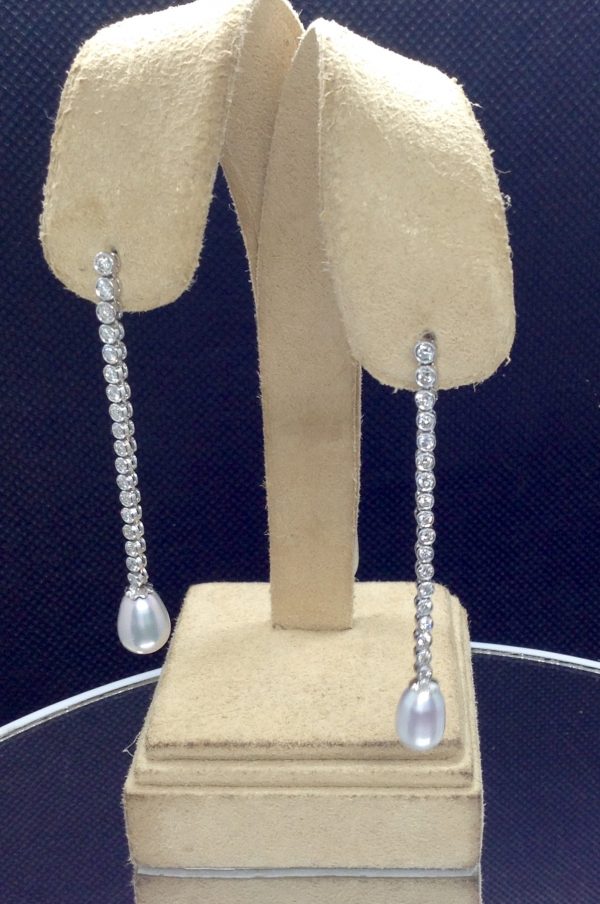 10mm South Sea Pearl Drops with 1.00 Ct Diamond Long Drop Dangle 18k White Gold Earrings hanging on fake ears (front view)