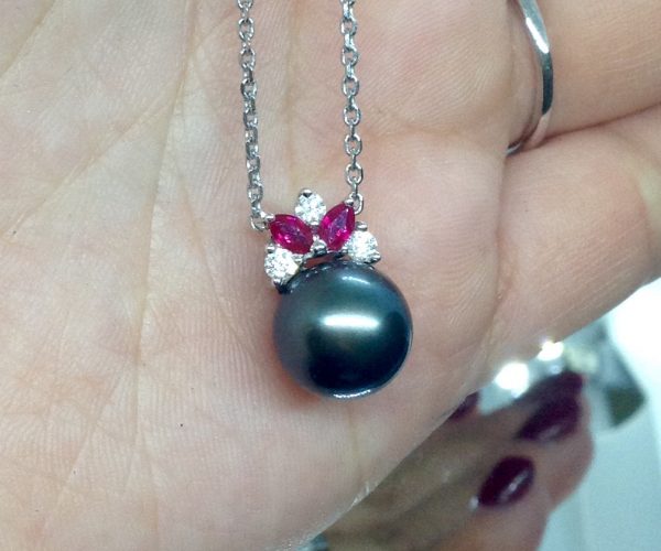 A woman holding a 11mm Tahitian Pearl with 0.12 Ct Diamond and 0.20Ct Ruby 14k White Gold Pendant