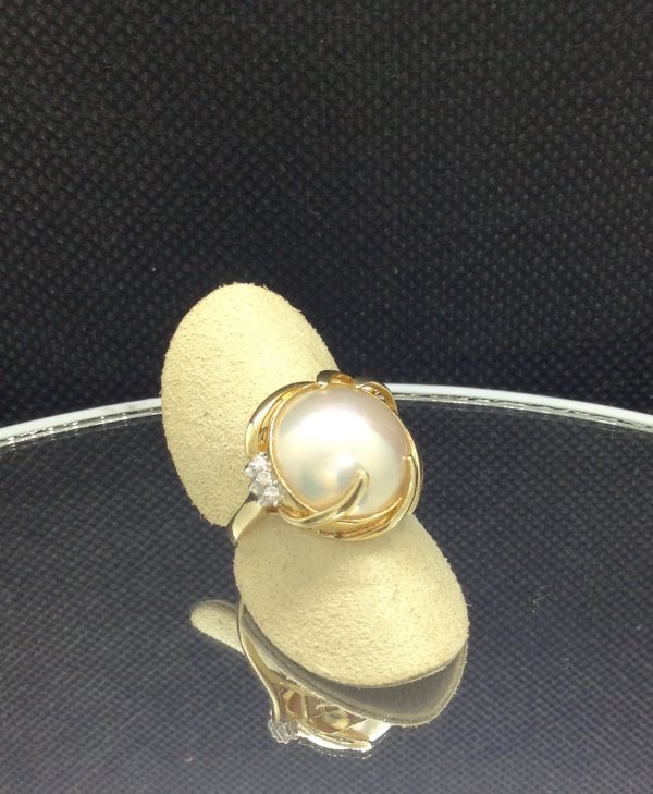 Alluring 13mm Mabe Pearl with 0.03 Ct Diamond Accents 14k Yellow Gold Ring on a piece of glass (side view)