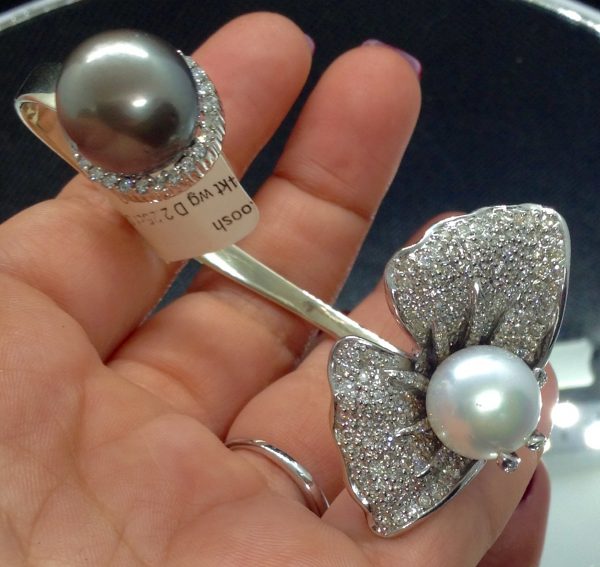 A woman holding a Ying-Yang 14k White Gold Bangle 13mm South Sea Pearl and 13mm Tahitian Pearl with 2.25 Ct Diamond