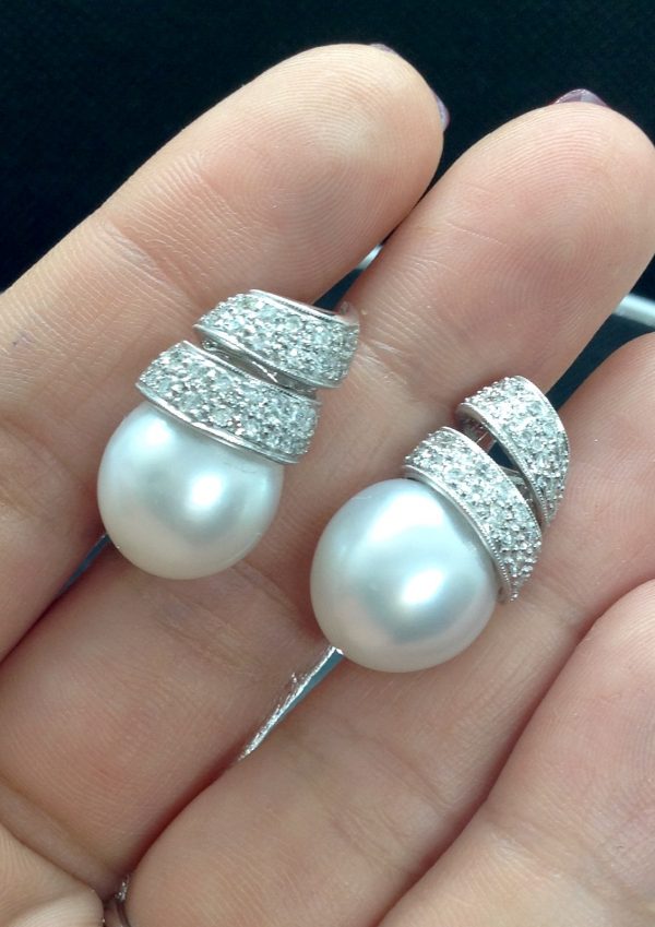 A woman holding 14mm South Sea Pearl 18k White Gold Earring with 1.25 Ct Diamond with a Twirling Design