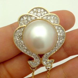 A woman holding a Vintage Hanging Brooch 14K Yellow Gold & 1CT VS Diamonds w/ South Sea Pearl