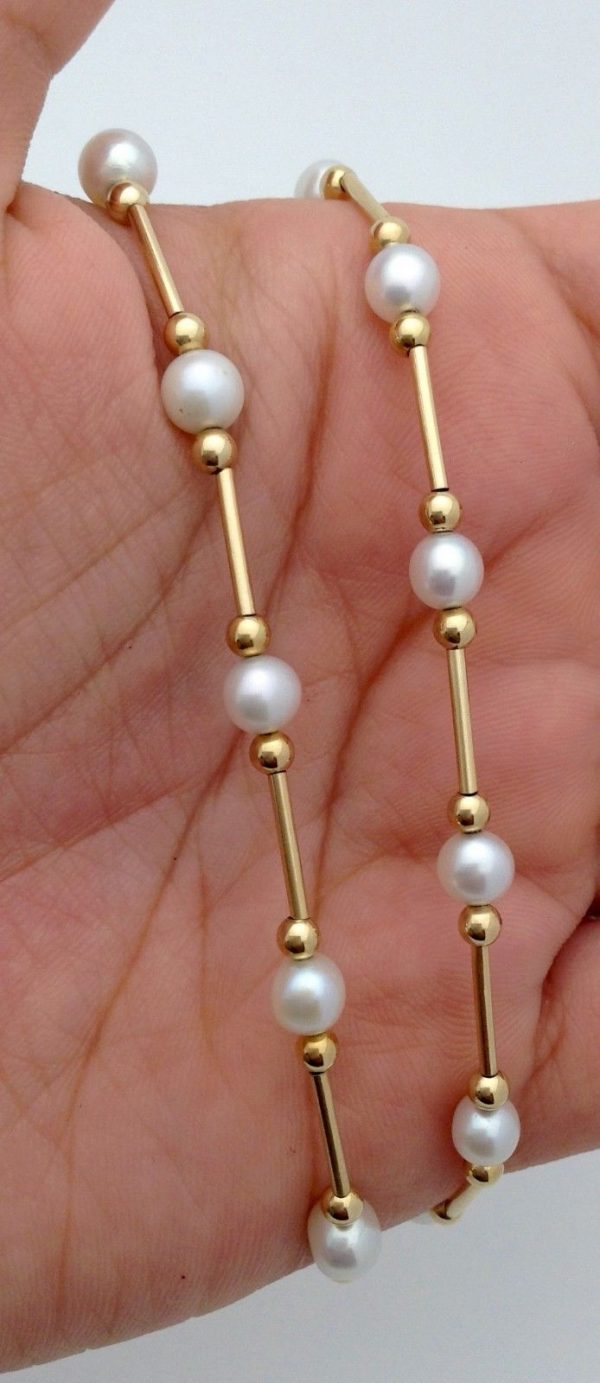 A woman holding Classy 4mm Akoya Pearls w/ 14k yellow gold beads and bars