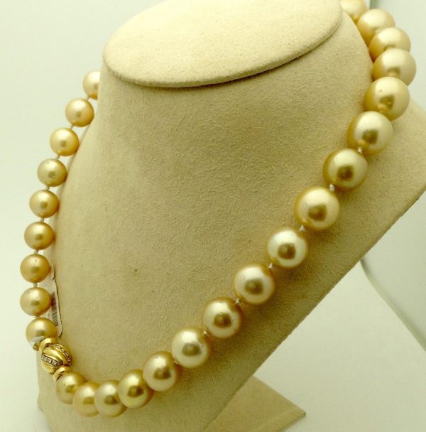 A side view of golden South Sea Pearls 16mm 18k Yellow gold Clasp w/ VS Diamonds accents on a fake neck
