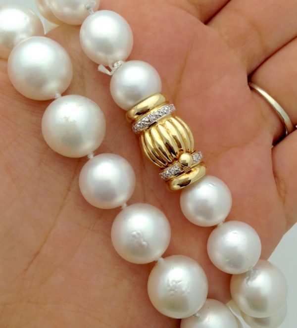 A woman holding South Sea Cultured Pearls 13mm 18k Yellow Gold Clasp w/ VS Diamonds accents