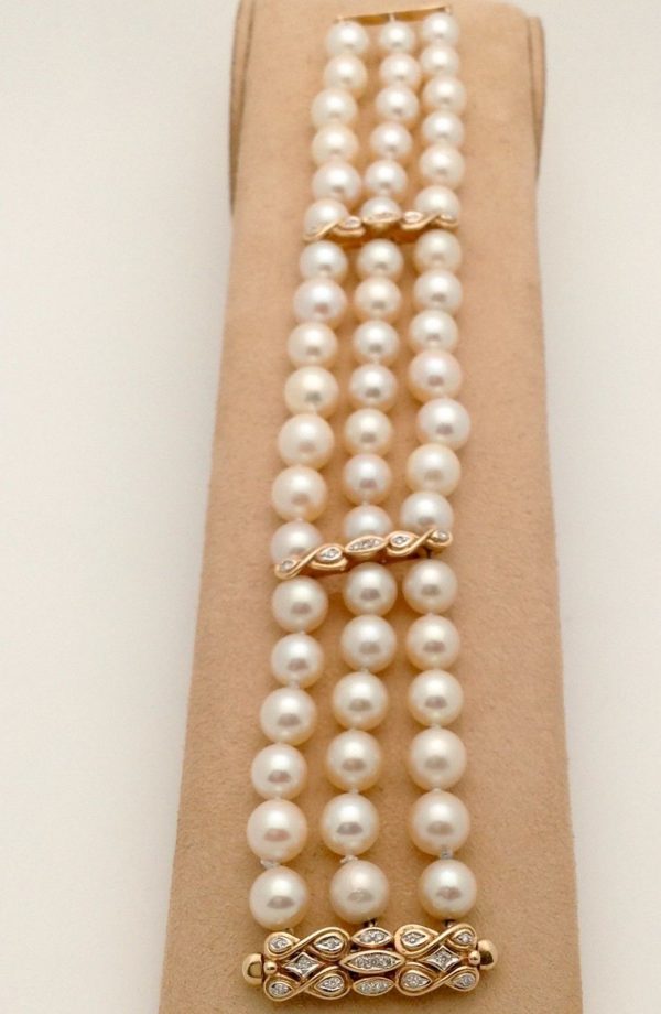 A woman holding 3 Row South Sea Cultured Pearls 8mm 18k Yellow Gold Clasp w/ VS Diamonds accents on a platform