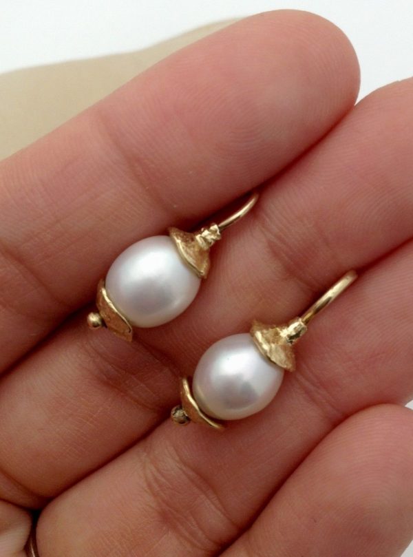 A person holding two Short Drop South Sea Cultured 10mm Pearls w/ 14k Yellow Gold Rustic Accents