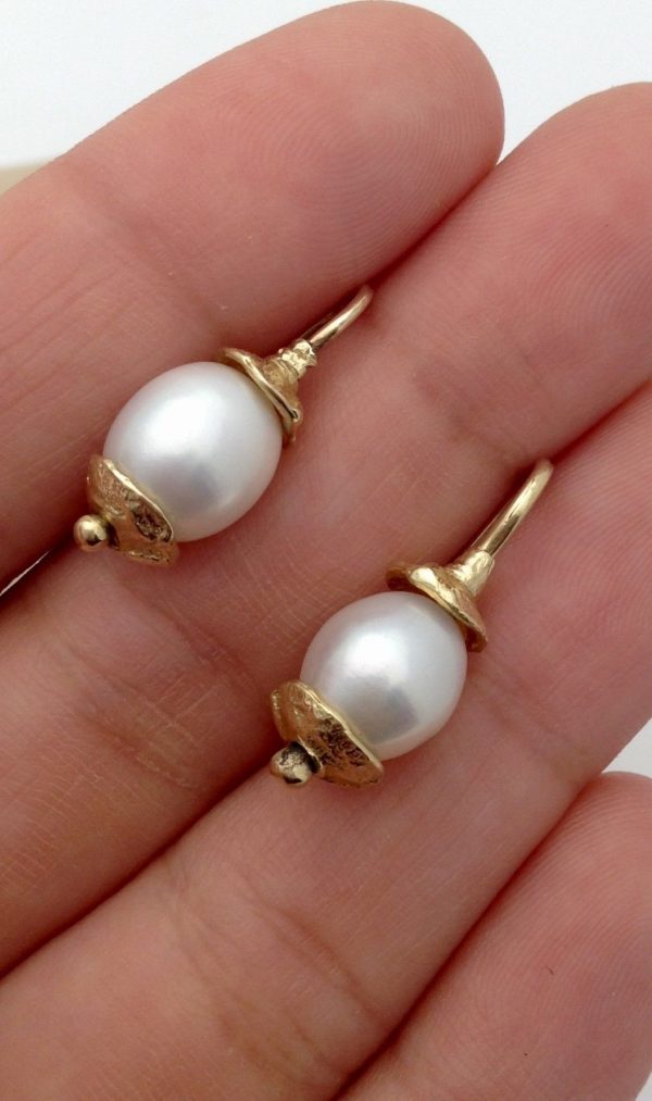 A person holding two Short Drop South Sea Cultured 10mm Pearls w/ 14k Yellow Gold Rustic Accents