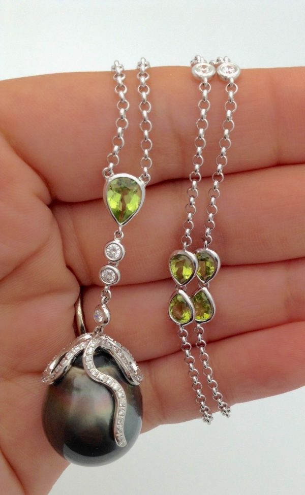 A woman holding a Tahitian Pearl w/ Peridot Accents & 1.00 CT VS Diamonds 14k White Gold Necklace