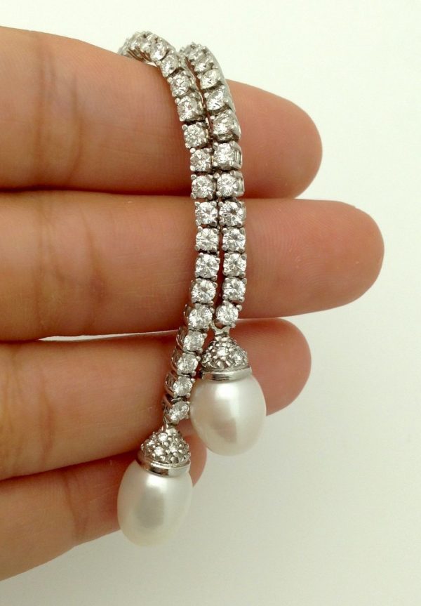 A woman holding a 4.50ct VS Diamond 18k White Gold Tennis Necklace w/ 11mm South Sea Pearls