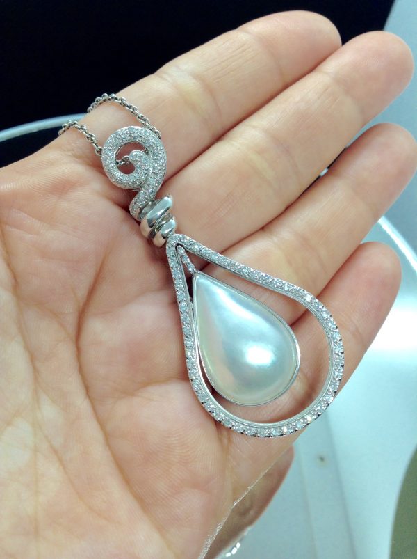 A woman holding 18.7 Ct Mabe Pearl with 1.00 Ct Diamond 14k White Gold Pendant with 16" 14k White Gold Chain