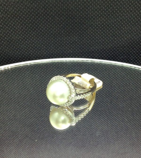 A side view of Elegant 11mm South Sea Pearlwith 0.75 Ct Diamond 18k White Gold Cathedral Ring on a piece of glass