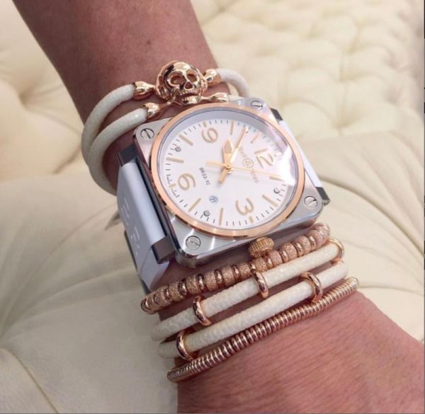 A woman with bracelets and a square white designer watch on her hand